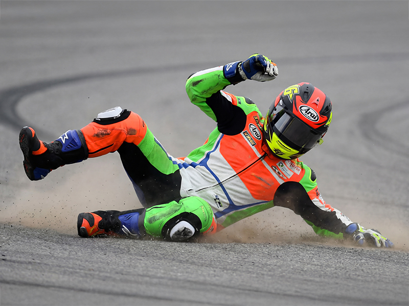 Motorcycle racer in brightly coloured leathers sliding down a race track